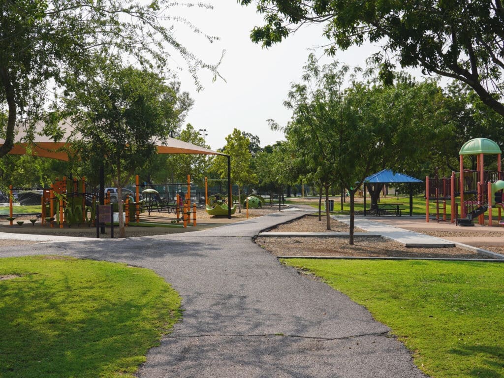 A sidewalk leads to two playgrounds.