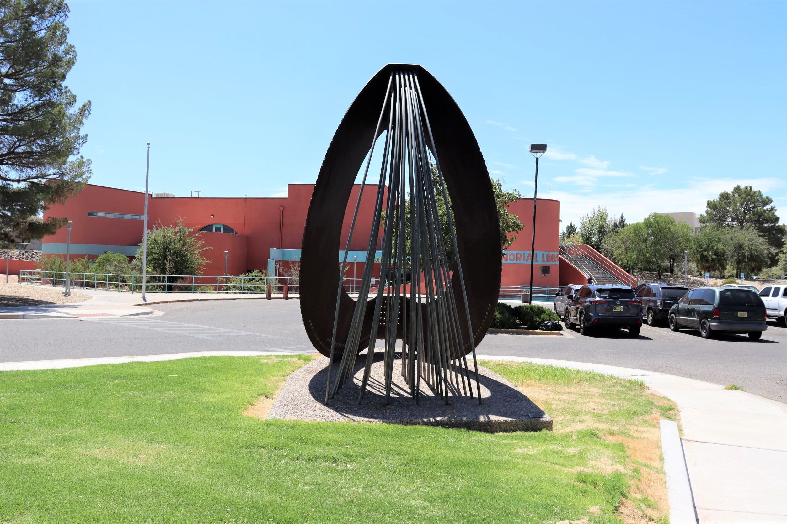 photo of sculpture made of corten steel in front of library building