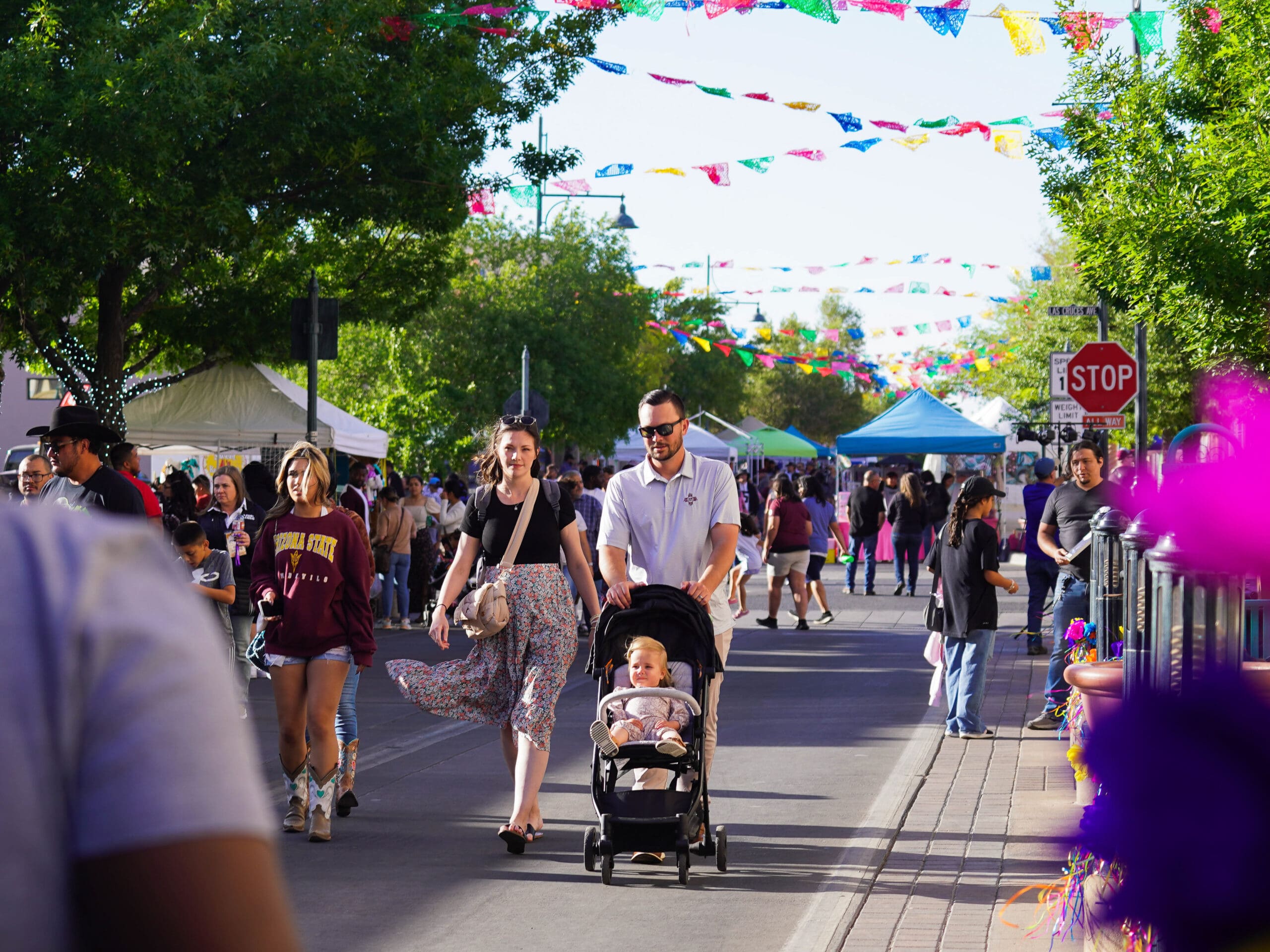 A family walking down a busy street with pop up tents.