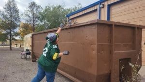 Person throwing trash into a large metal container