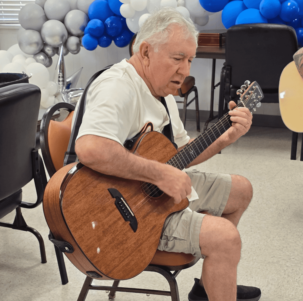 Senior male playing guitar at Eastside