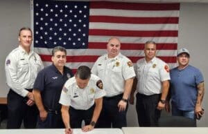 Firefighters standing in front of a flag