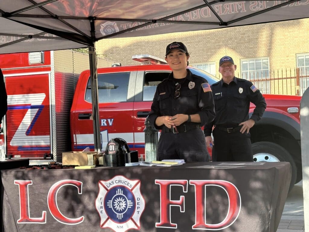 Two Las Cruces Fire Department firefighters standing behind table at National Night Out 2024