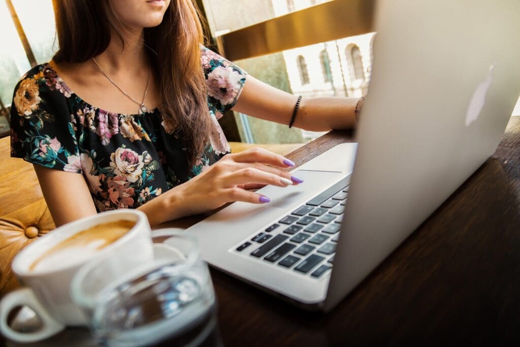 Woman sitting at desk with open laptop and typing