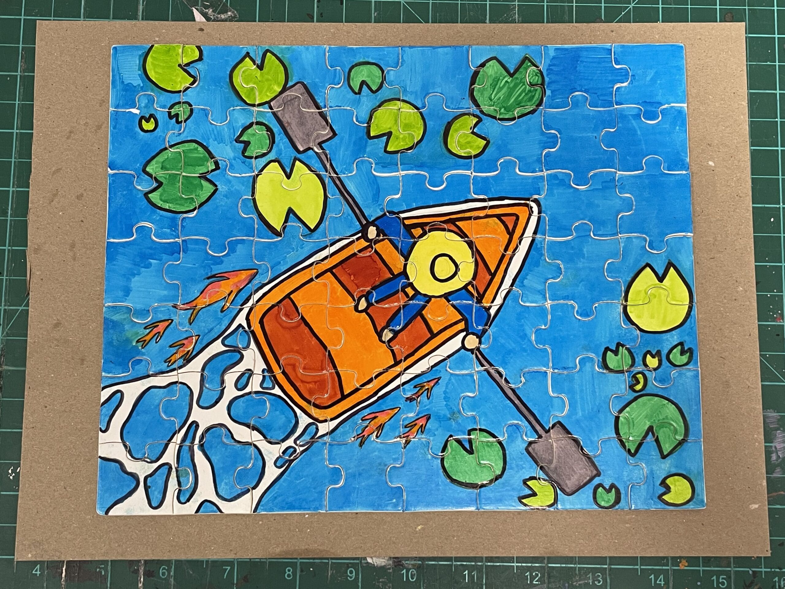 Puzzle of a man in a boat in the water. Fish and Lilly pads are on each side of the boat