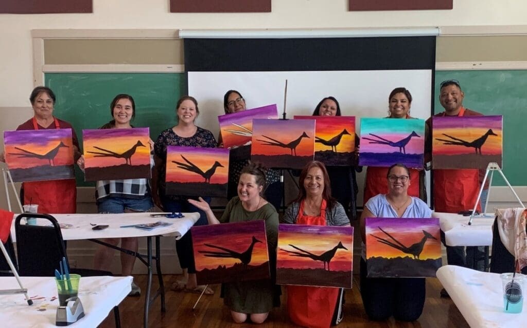 Students holding their paintings of roadrunners