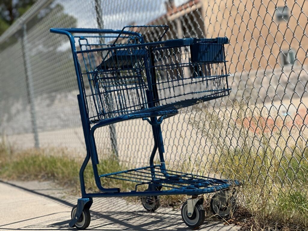 Shopping cart on sidewalk by a fence