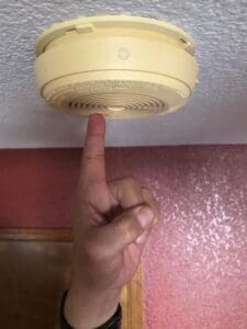 Finger pointing at smoke detector