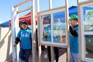 Student apprentice members installing a window in a frame.