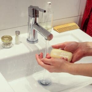 Hands holding soap under faucet