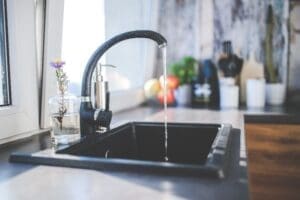 Water faucet with water coming out into a sink.