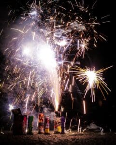 Fireworks set on the ground emitting sparks at night.