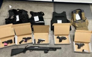 Guns in a box on the floor with bulletproof vests.