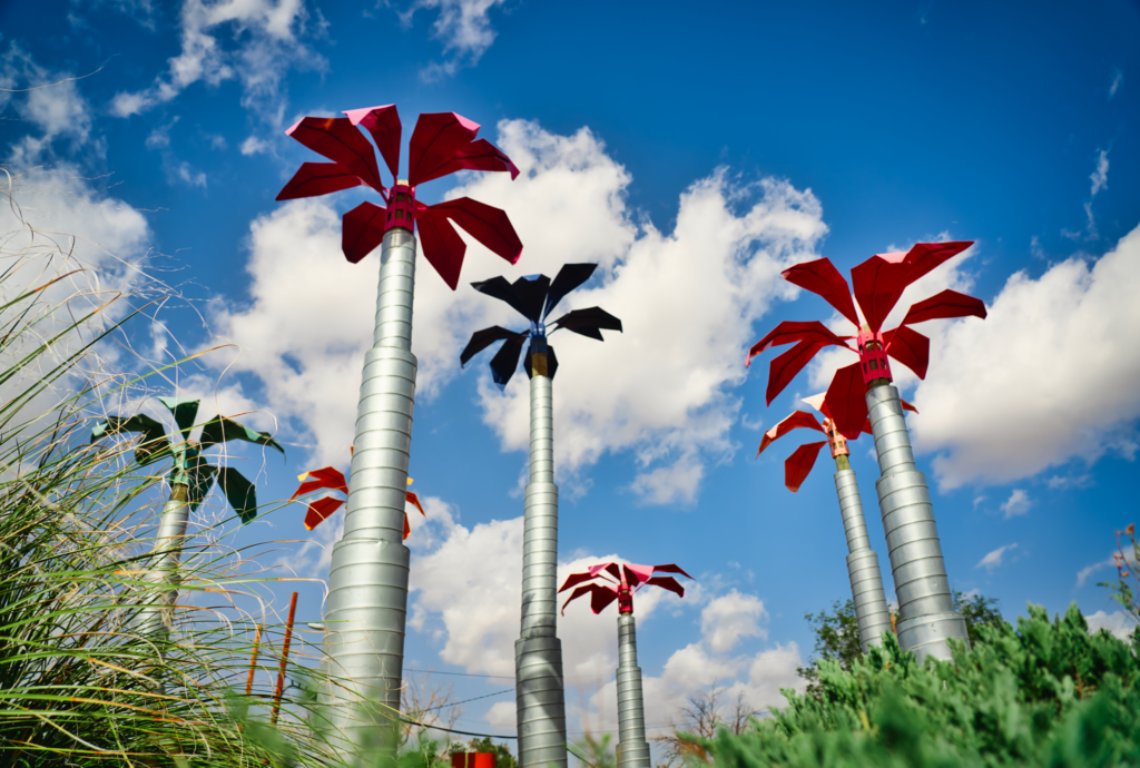 Metal palm trees in front of clouds.