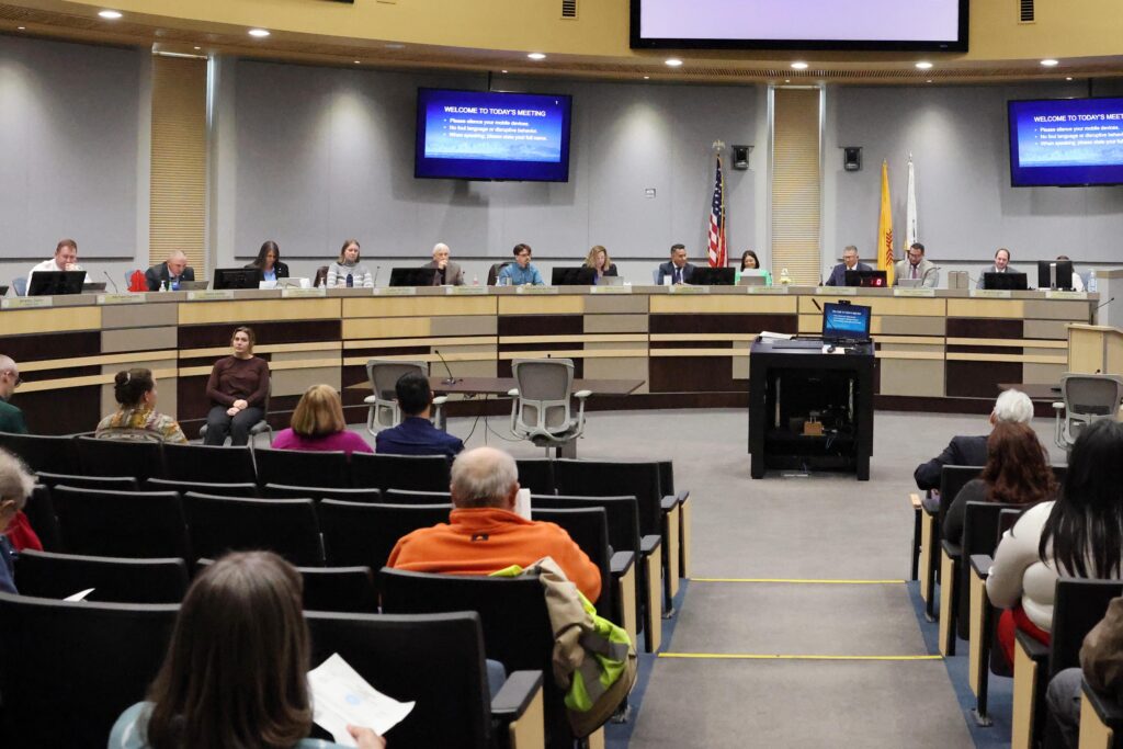 People sitting in the audience section looking at the councilors and staff at a City Council meeting.