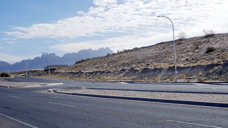 A street with a hill and mountains behind it.