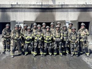 Group of firefighters standing in front of a building.