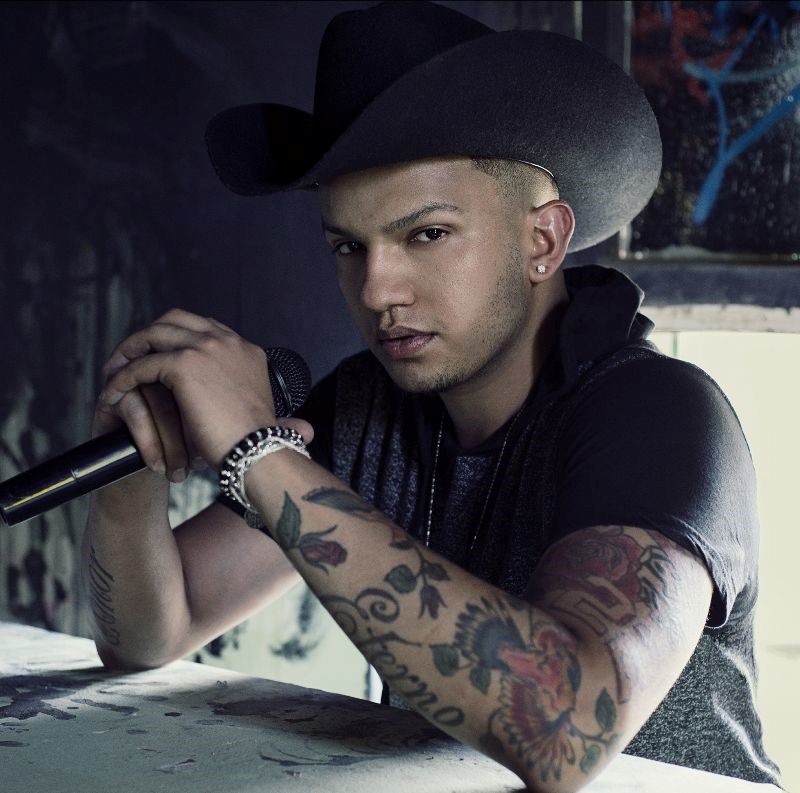 Man with a cowboy hat sitting down with a microphone.
