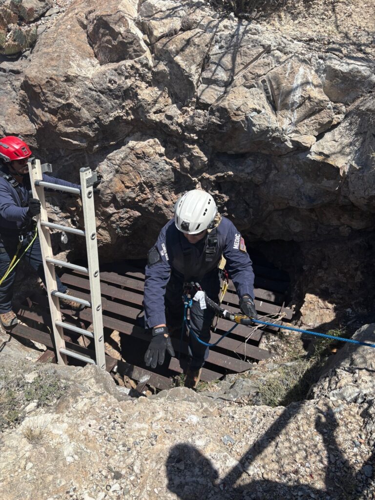 Emergency personnel rappelling into a mine shaft.