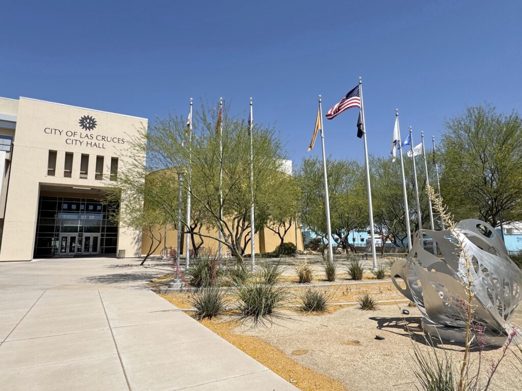 Front entrance to City Hall with flag poles and flags on the right side.