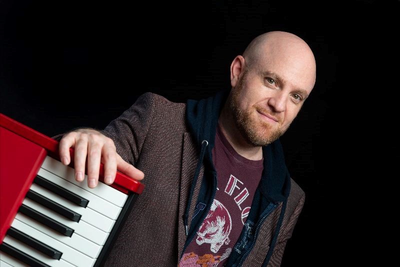 Man with his hand on the side of a keyboard.