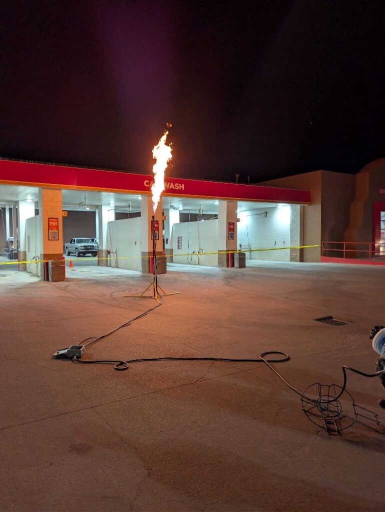 Propane torch burning in front of a car wash bay.