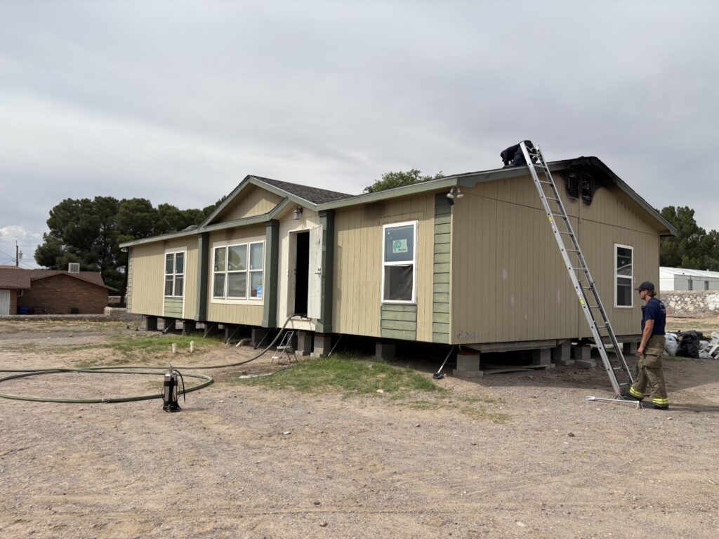 Firefighter stands near a ladder placed on a mobile home after putting out a fire.