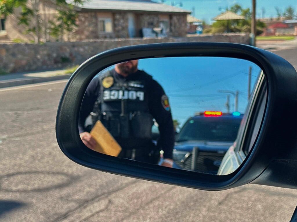 Police officer in the rear-view mirror of a vehicle.