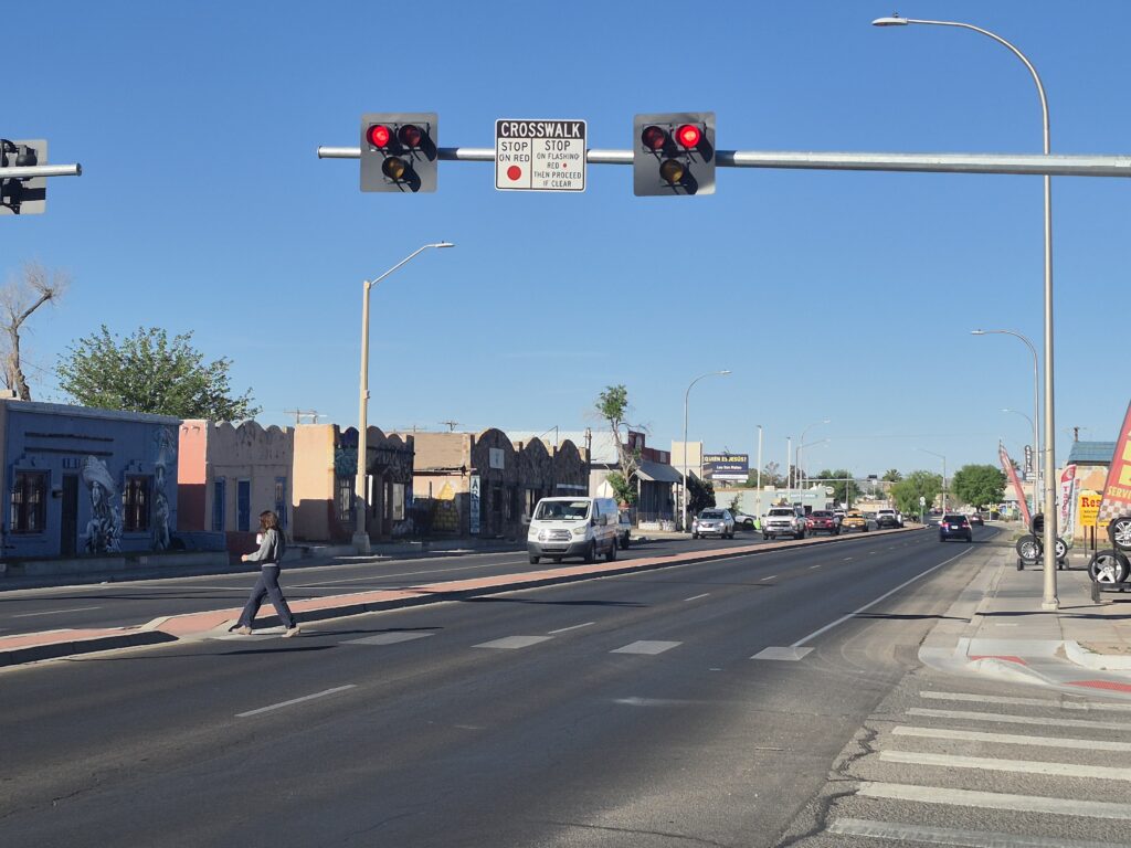Woman walking across the street under the assistance of a H.A.W.K. system for pedestrian crossing.