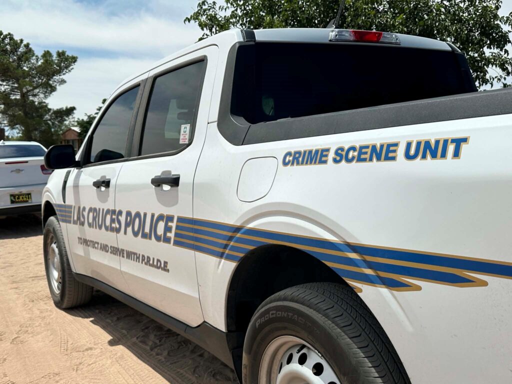 City of Las Cruces crime scene unit vehicle parked in a dirt lot.