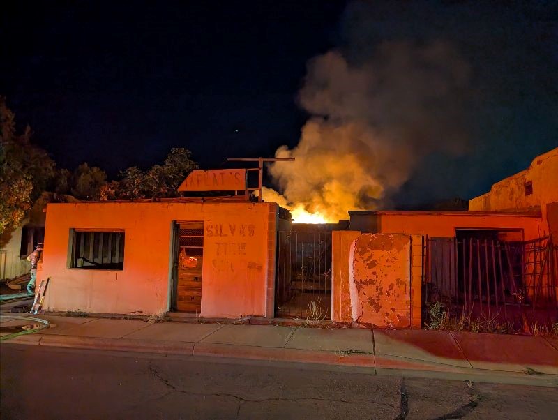 Front of a building at might with fire coming from the back.