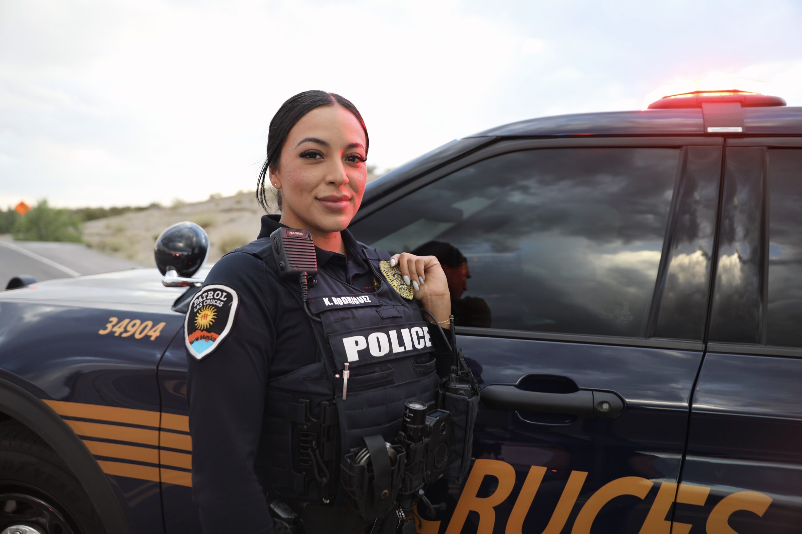Female LCPD officer standing in front of a cruiser in full gear