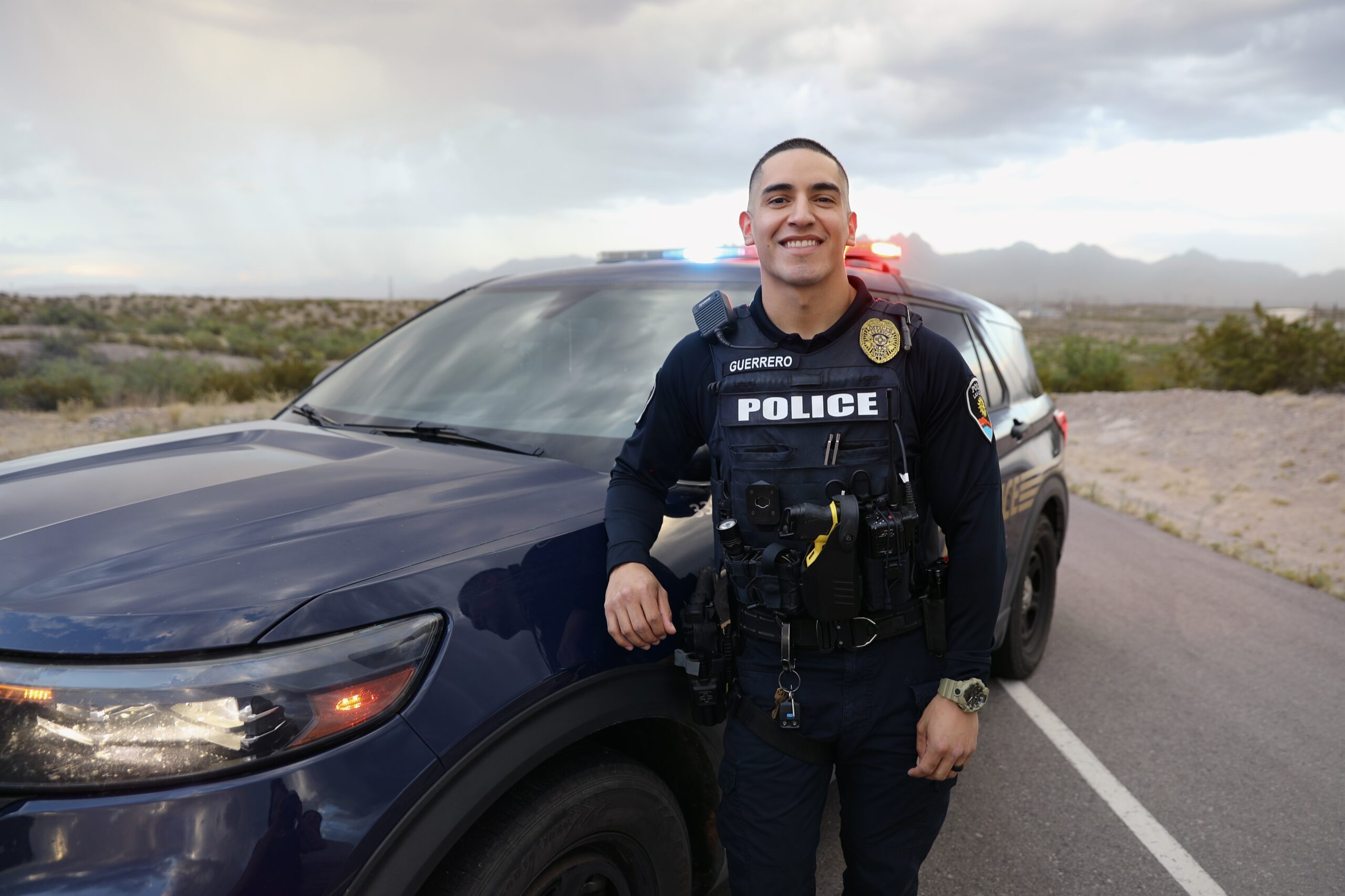 A younger LCPD officer standing in front of a cruiser and smiling at the camera.