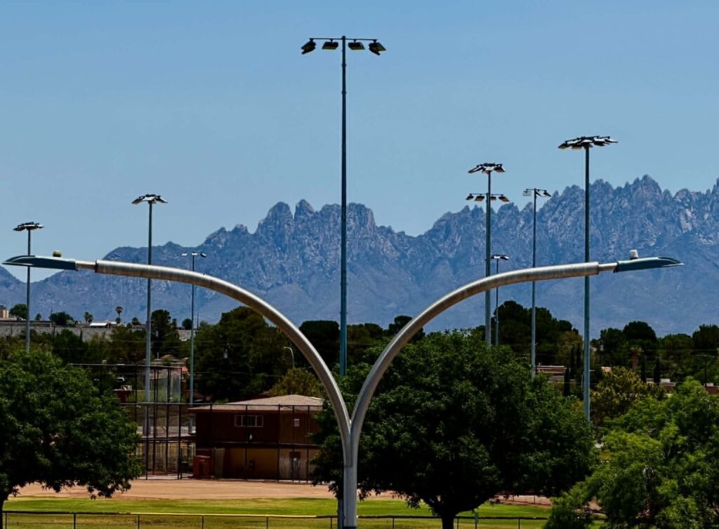 Light poles with trees and mountains in the background.