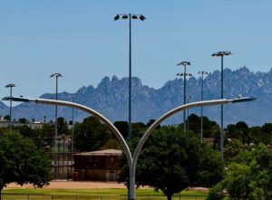 Light poles with trees and mountains in the background.