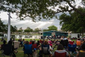 Band plays on stage at Young Park while many people sit and watch.