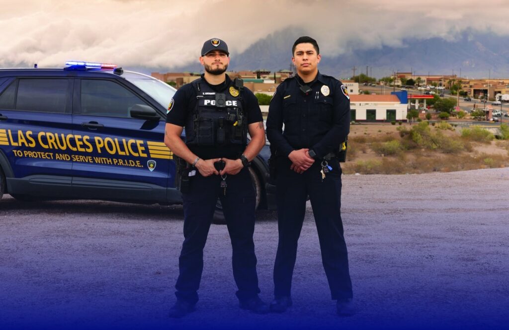 Two police officers standing in front of a police vehicle.