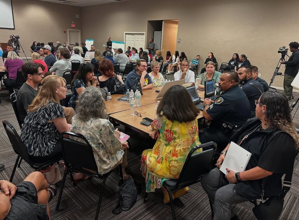 Police officers speaking to a group of people at a table.