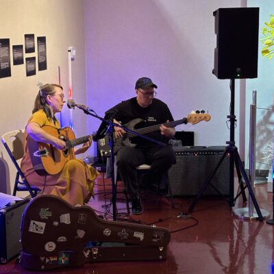 A pitcute of a duo playing guitars and singing in the Museum of Art.