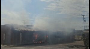 Single story apartment building with fire and smoke coming out.