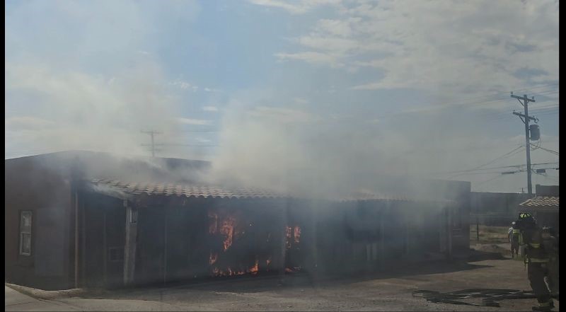 Single story apartment building with fire and smoke coming out.