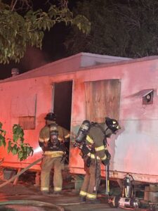 Firefighters looking into an abandoned mobile home.