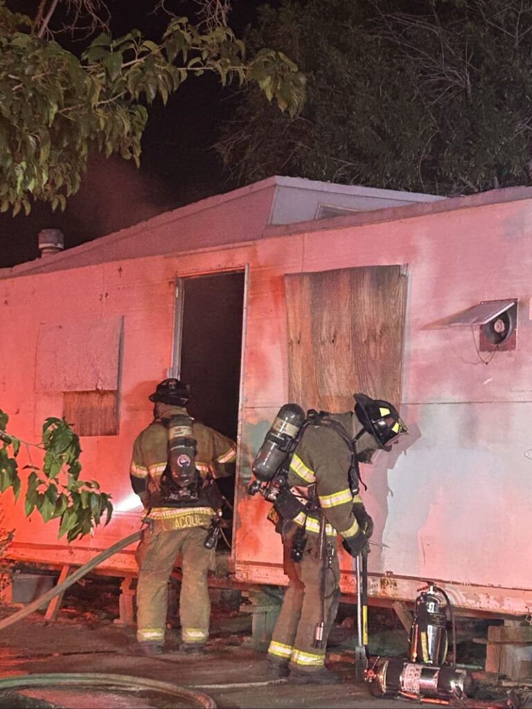 Firefighters looking into an abandoned mobile home.