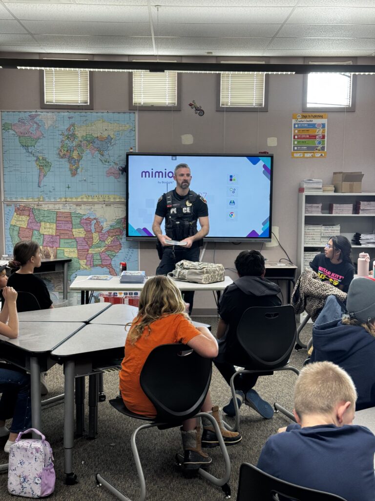 Police Office in the front of A classroom with a few students looking in his direction.