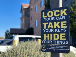 Sign posted on a pole with a building and vehicles in the background.