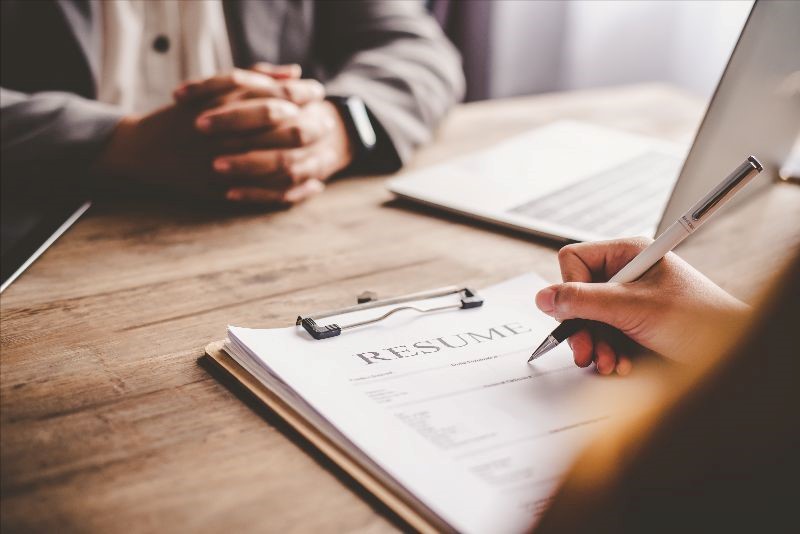 Paperwork on a table with a person on one side and another person on the other side.