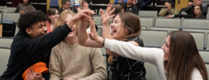 Group of young people in City Council Chambers giving each other a high 5.