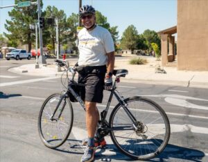 Man standing in the road with his bicycle.