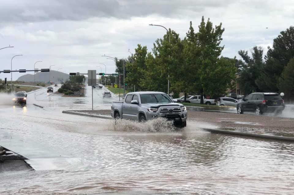 A truck driving through water in the road after a rain storm.