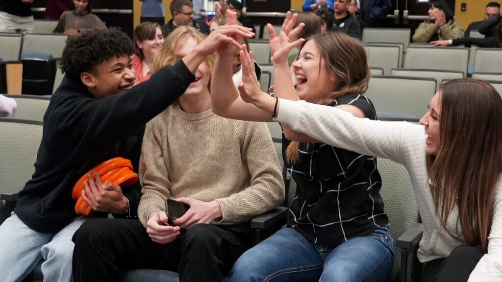 Kids sitting down doing a group high five.
